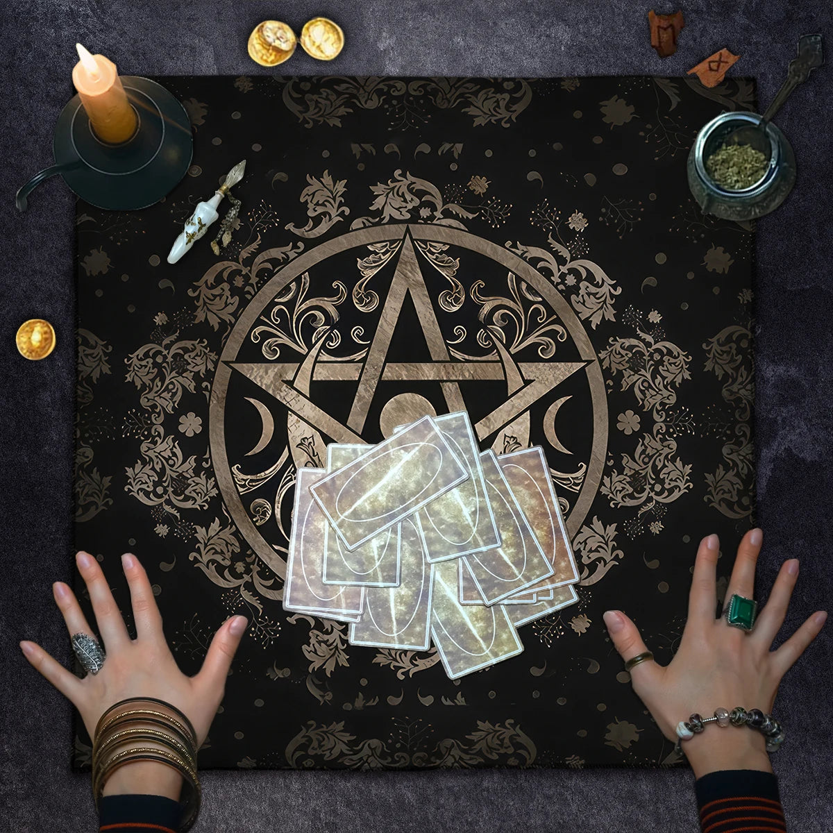 Tarot cards on a black cloth with a gold pentacle symbol, surrounded by candles and coins.