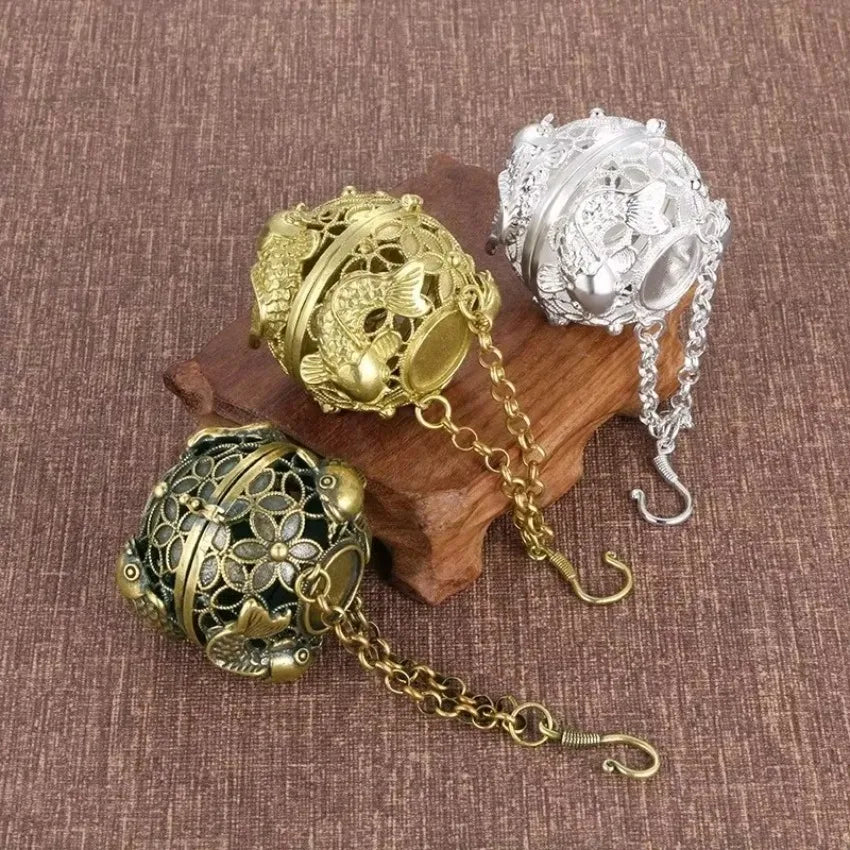 Three ornate spherical objects with chains on a textured brown surface