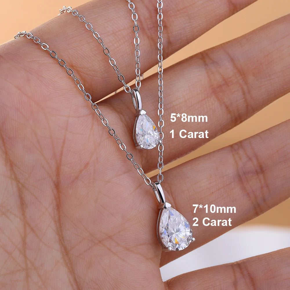 Two silver teardrop-shaped diamond pendants on a hand with size and carat weight labels.