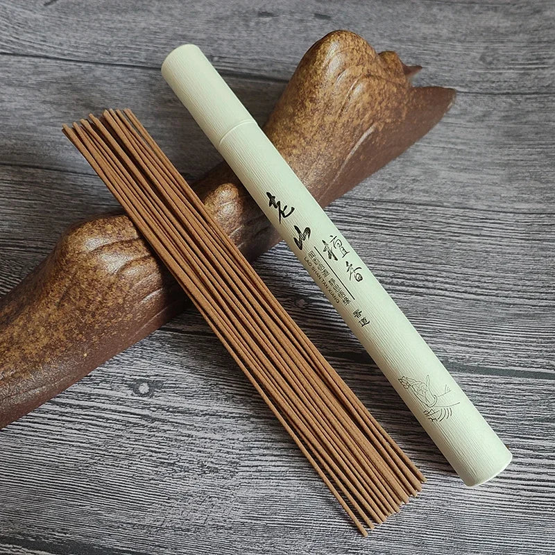 Incense sticks and their cylindrical container on a wooden surface
