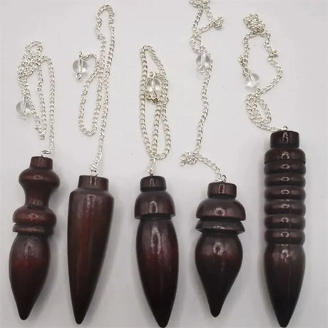 Set of five wooden pendulums on silver chains against a white background