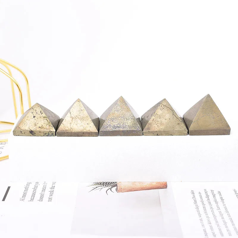 Five pyramid-shaped concrete blocks on a white surface with a pen and paper in the background.
