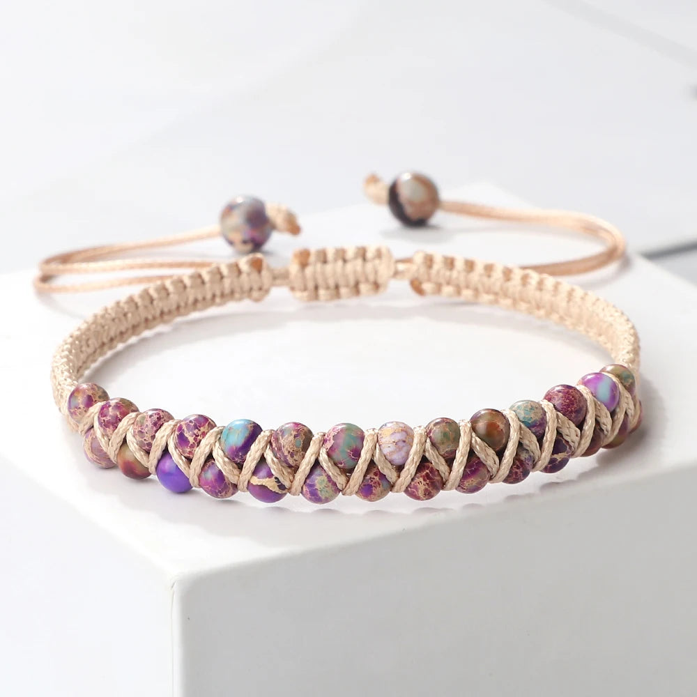 Beaded bracelet with purple and green stones on a white surface