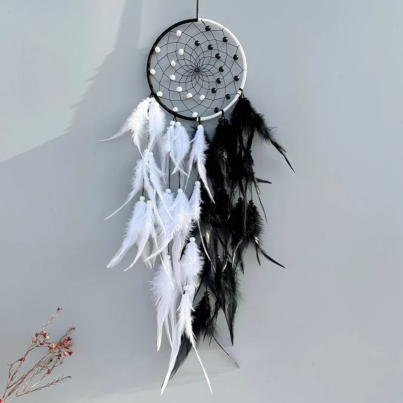 Black and white dreamcatcher with feathers against a light gray background