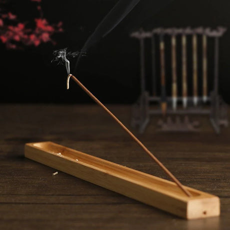 Incense stick burning on a wooden holder with a blurred background