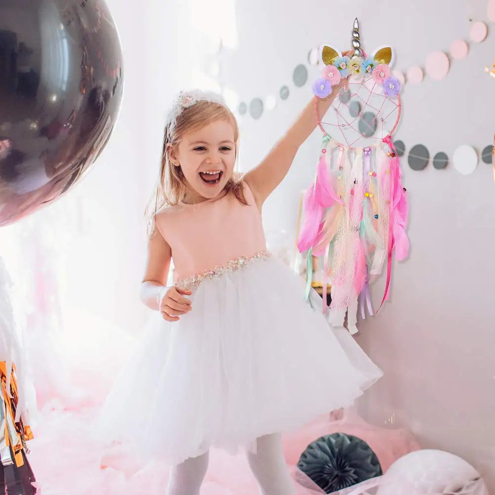 Young girl in a pink dress with a white tutu standing in a room decorated with balloons and a dreamcatcher.