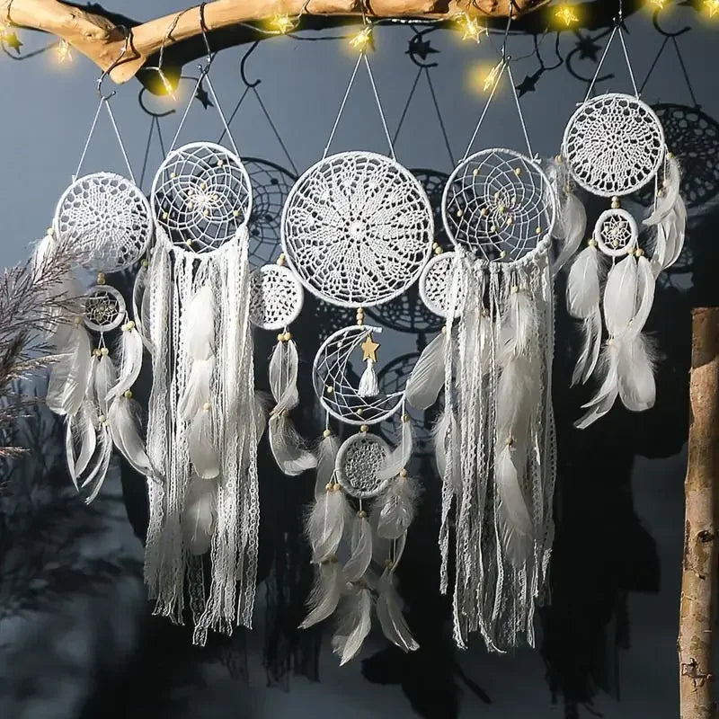 White dreamcatchers with feathers hanging against a dark background