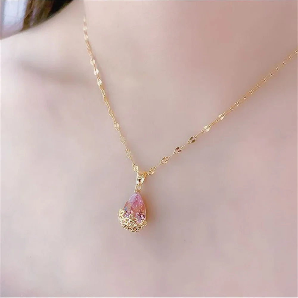 Gold necklace with a pink teardrop pendant on a soft pink background