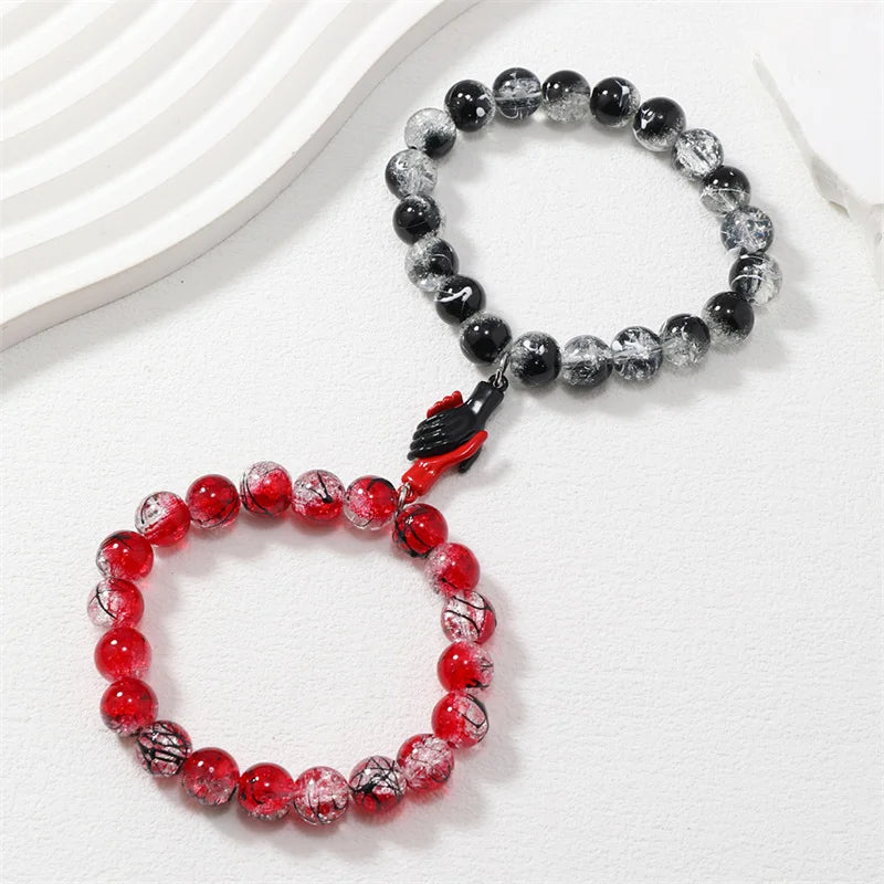 Two beaded bracelets, one red and one black and white, on a white surface.
