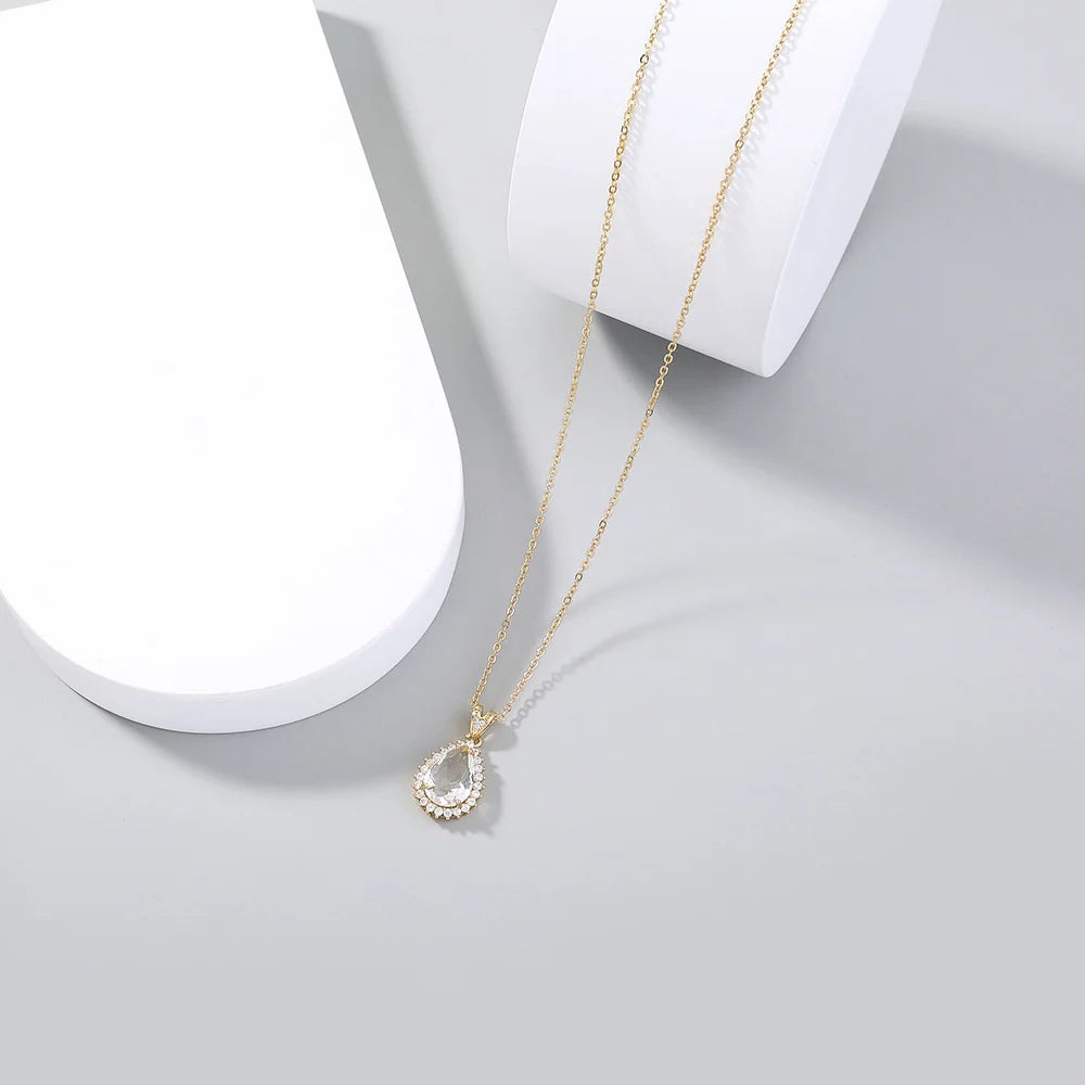Gold necklace with a teardrop pendant on a light gray background
