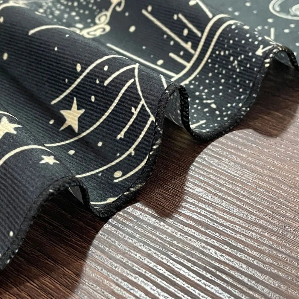 Black fabric with white star and moon pattern on a wooden surface