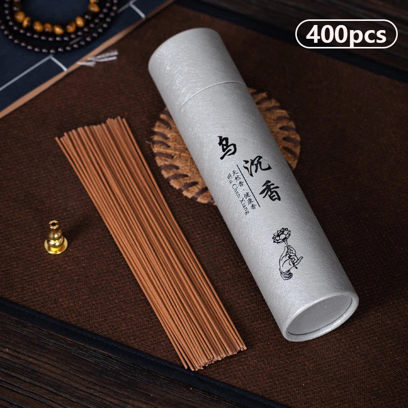 White cylindrical container with incense sticks on a dark surface
