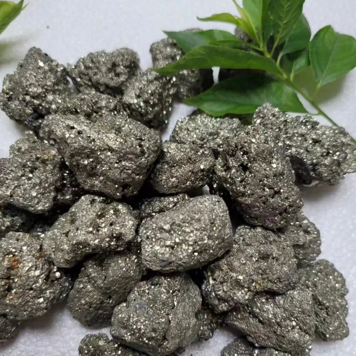 Pile of metallic rocks with green leaves on a white background