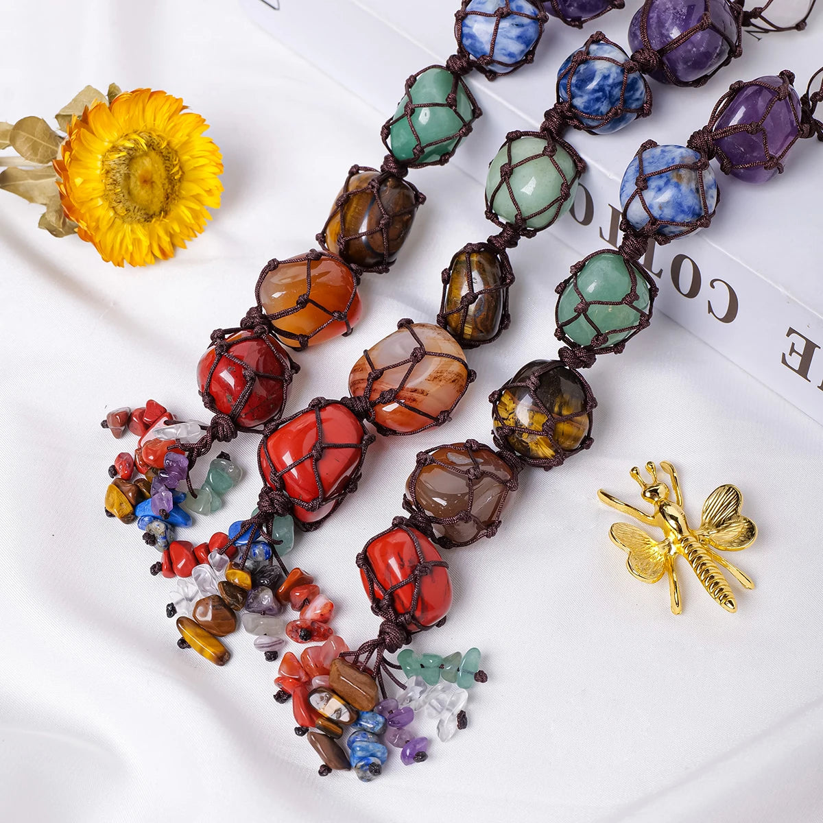 Colorful gemstone necklace with a yellow flower and gold insect on a white background