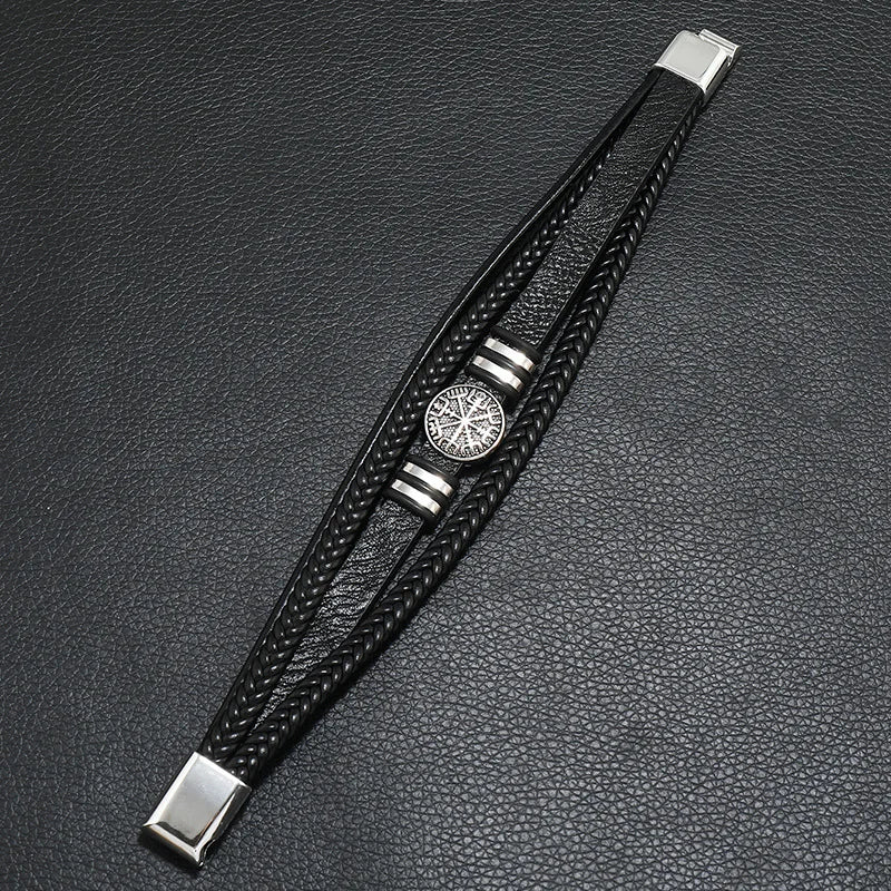 Black leather bracelet with silver accents on a dark textured surface