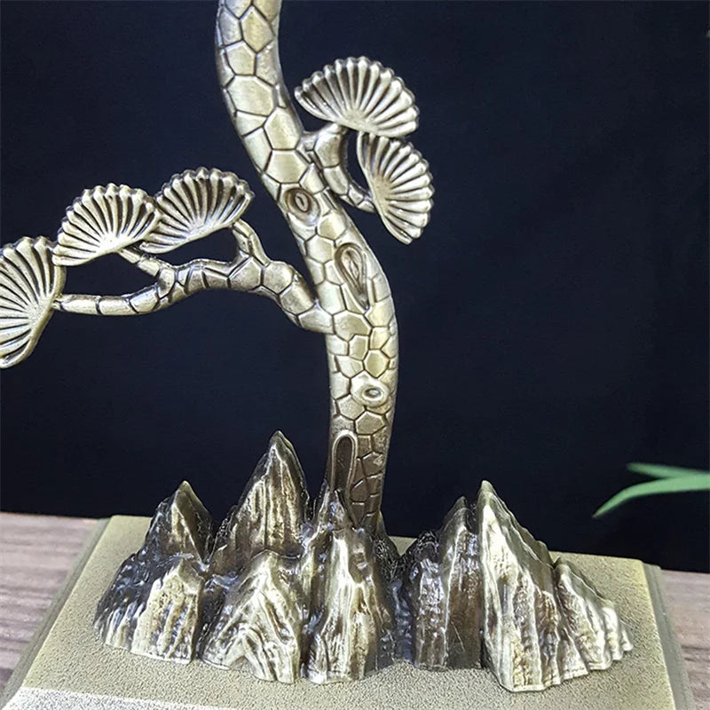 Metallic sculpture of a tree with abstract mountain-like base on a dark background