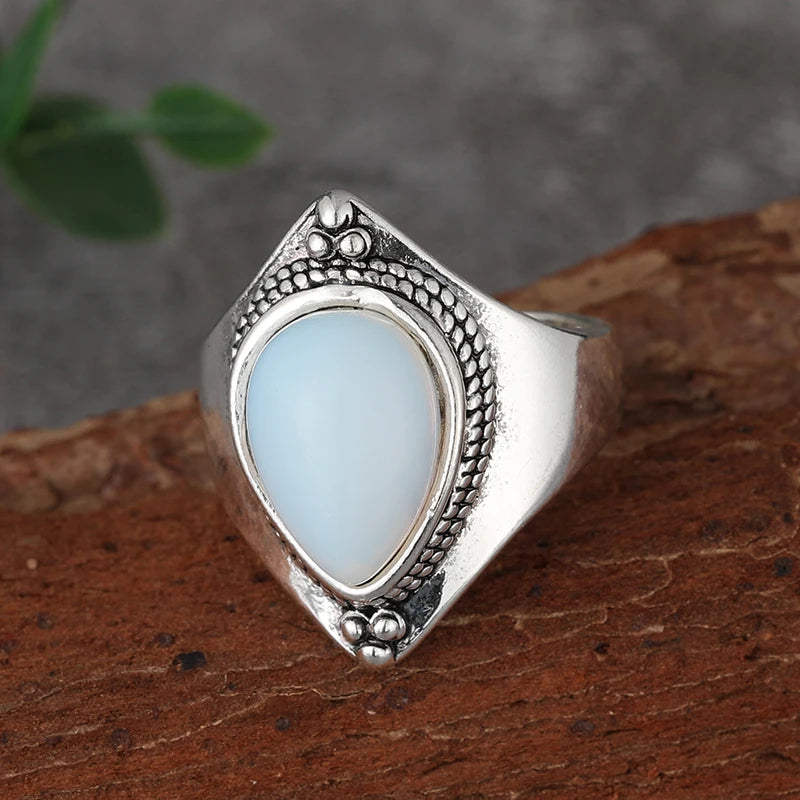Silver ring with a light blue stone on a wooden surface