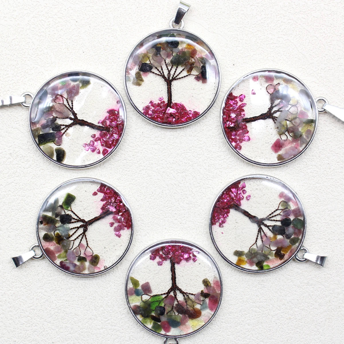 Set of six round pendants with tree designs and pink flowers on a white background