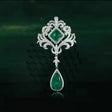 Ornate brooch with emerald stones on a dark background