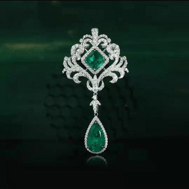 Ornate brooch with emerald stones on a dark background
