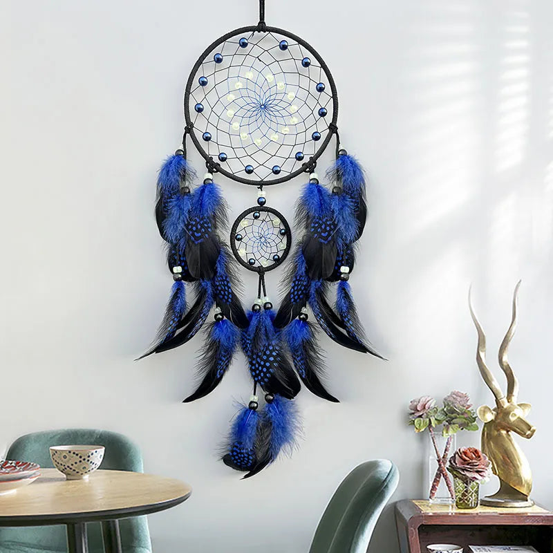 Blue and black dreamcatcher hanging on a white wall with decorative elements below.