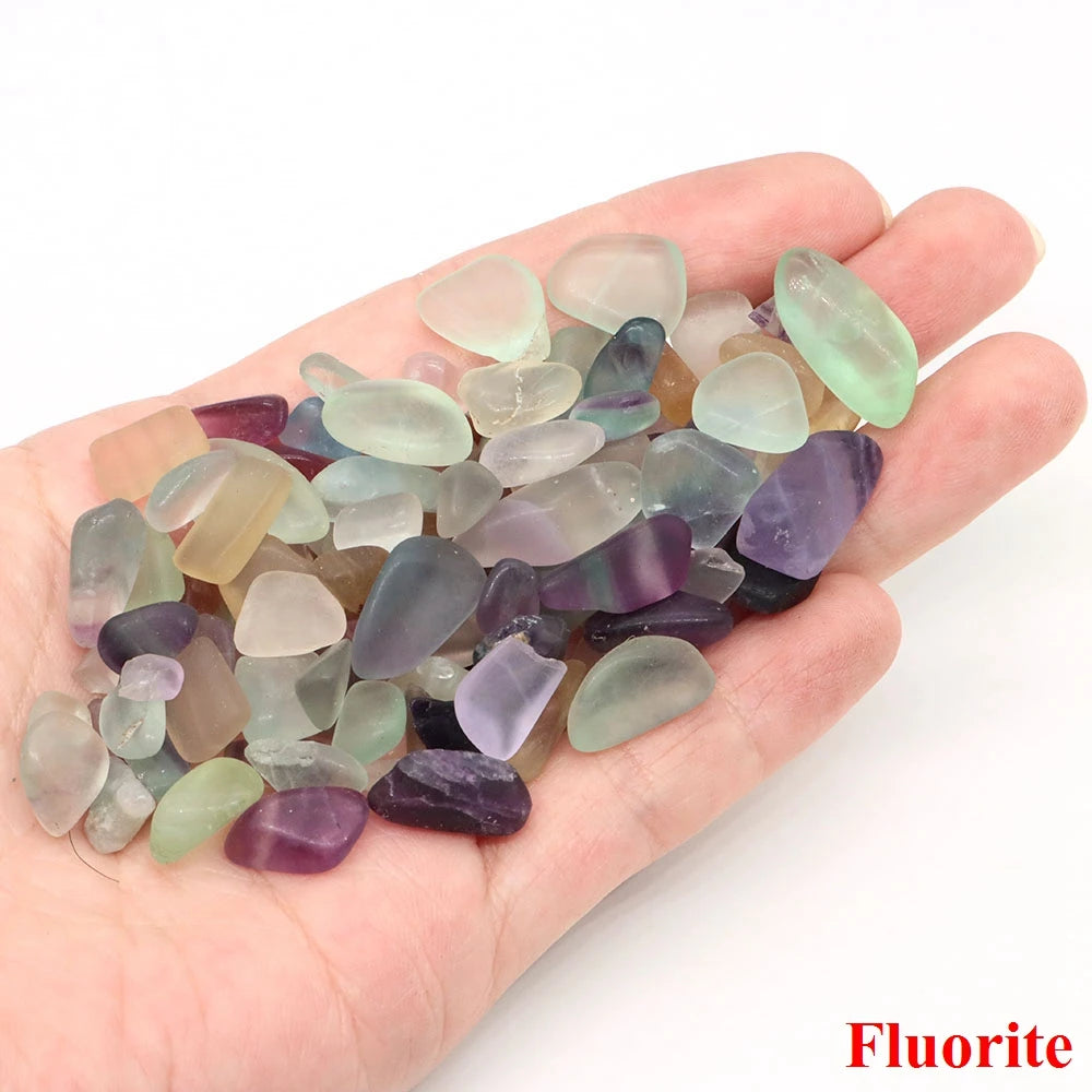 Hand holding a collection of multicolored fluorite crystals on a white background