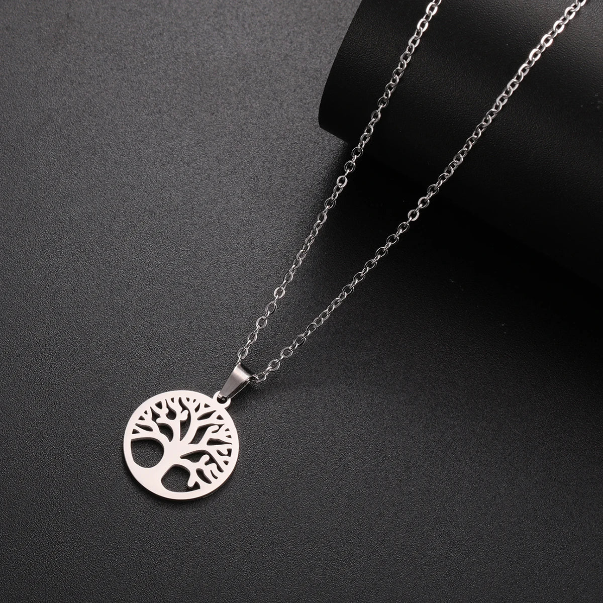 Silver necklace with a tree of life pendant on a dark gray background