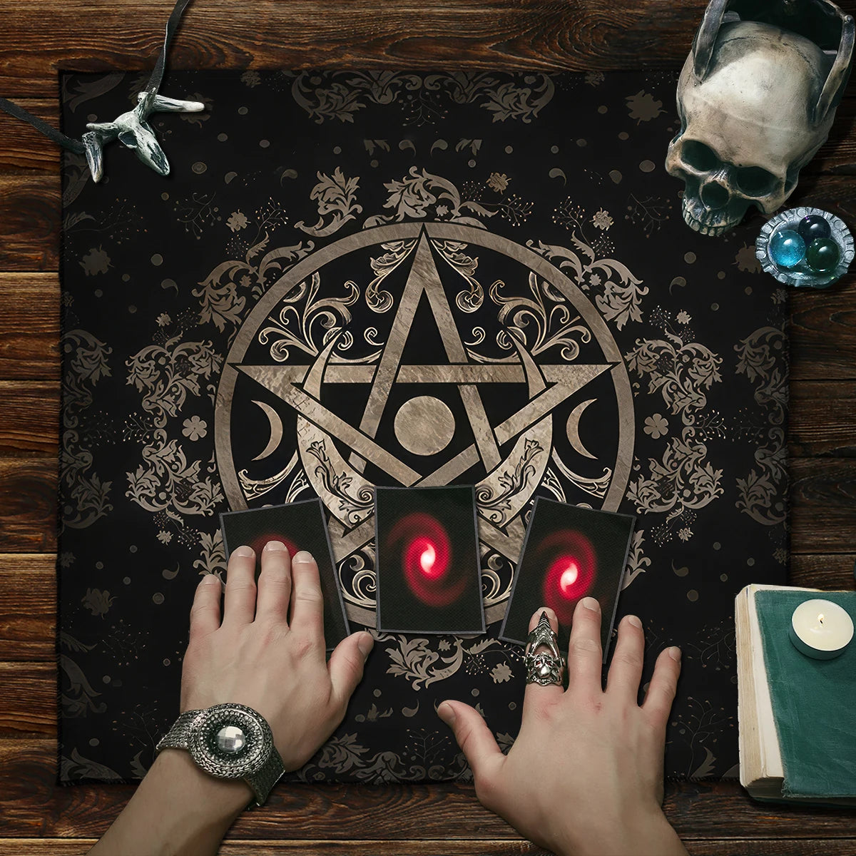 Hands on a mystical cloth with a pentagram design, surrounded by tarot cards and a skull.