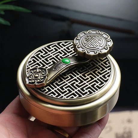 Brass incense burner with intricate designs held by a hand against a blurred background