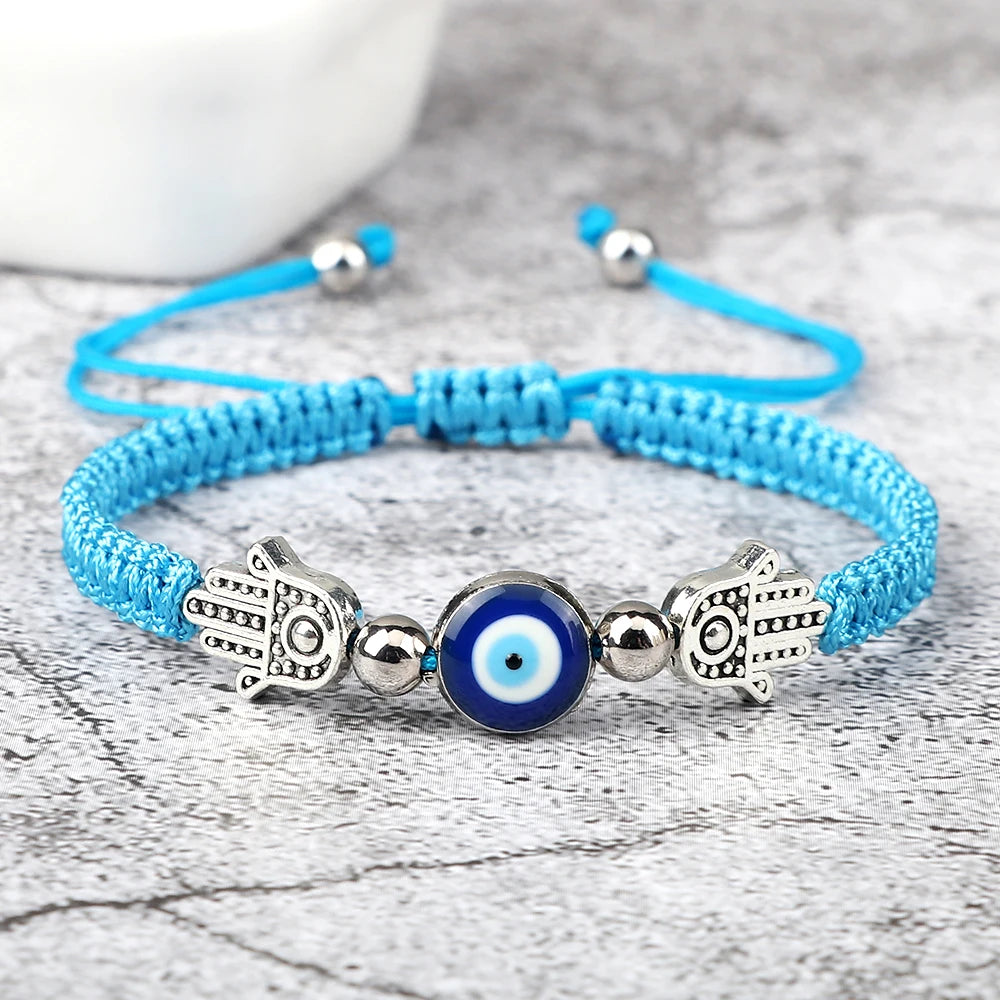Blue braided bracelet with Hamsa hand and evil eye charm on a wooden surface
