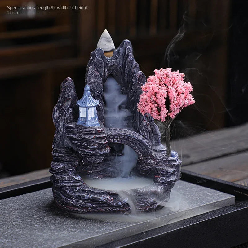 Decorative smoking fountain with mountain and cherry blossom design on a dark background