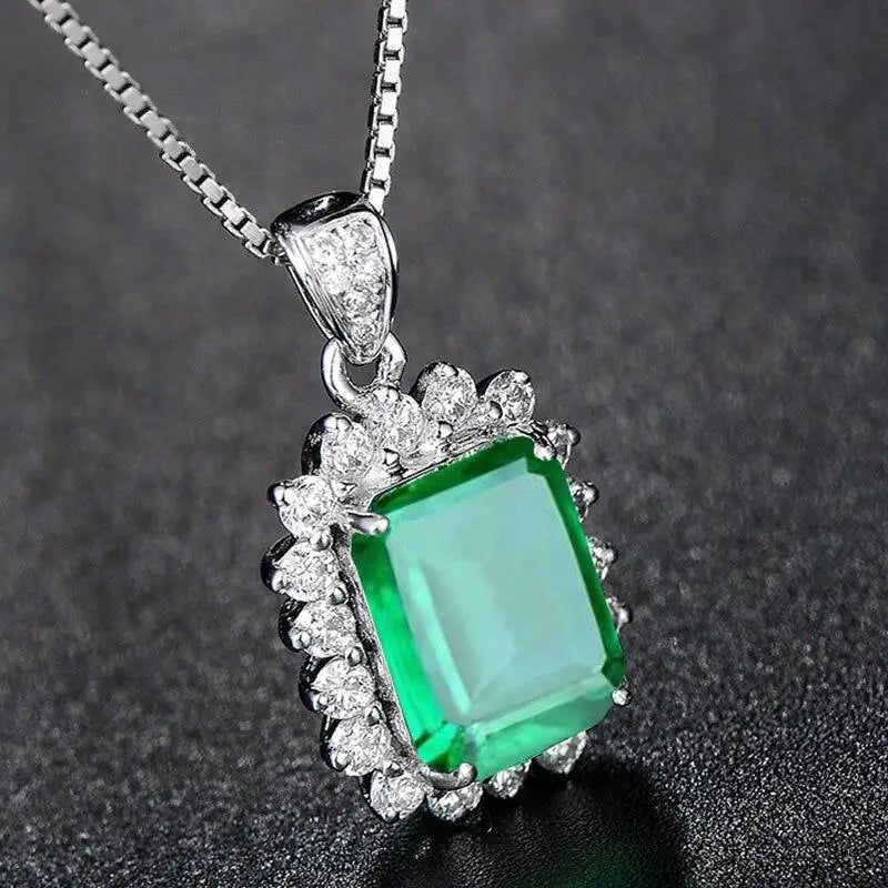 Green gemstone pendant with diamond accents on a dark background