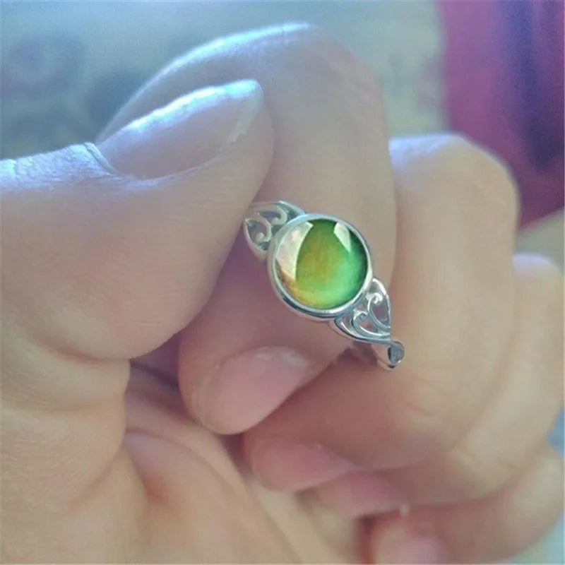 Close-up of a hand wearing a silver ring with a green gemstone.
