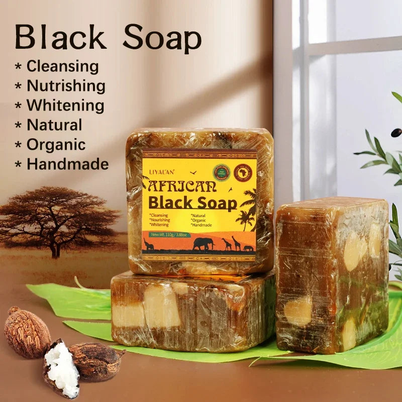 Two bars of African Black Soap with a label, surrounded by leaves and nuts on a neutral background.