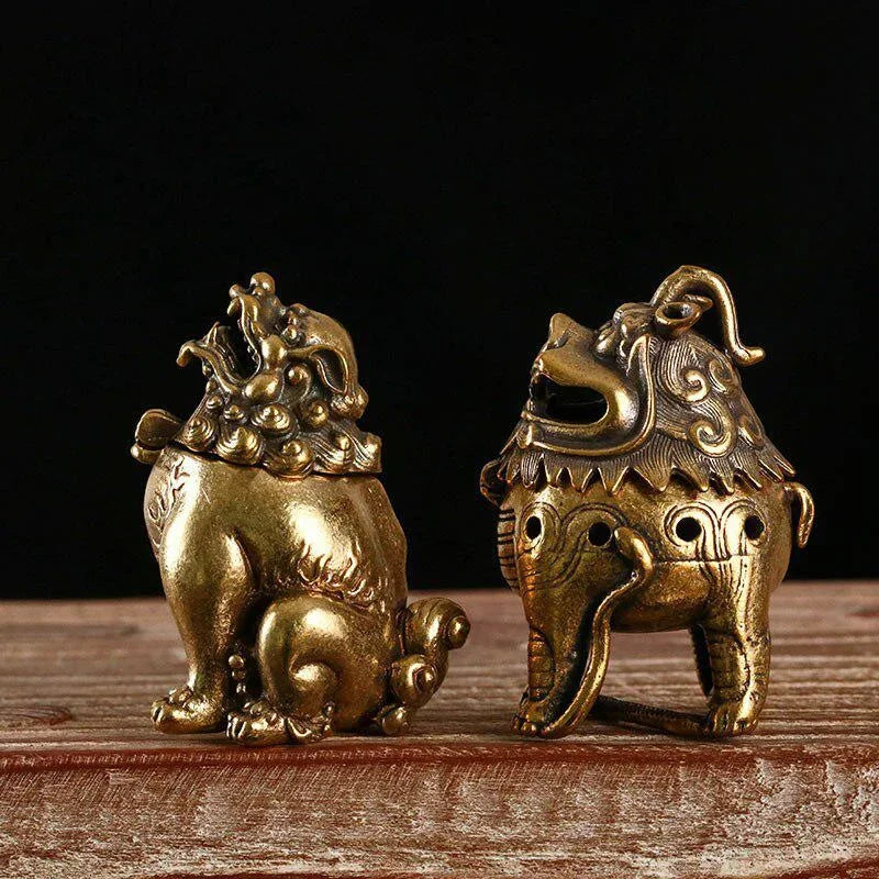 Two ornate brass lion statues on a wooden surface with a dark background