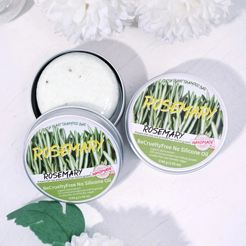Three tins of Rosemary shampoo bars on a white background with green leaves.