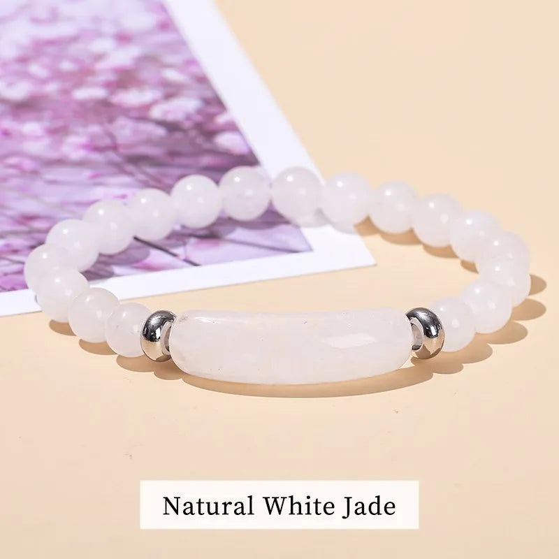 White jade bracelet with silver accents on a beige surface
