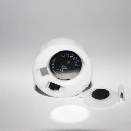 White battery holder with a CR2032 battery on a gray background