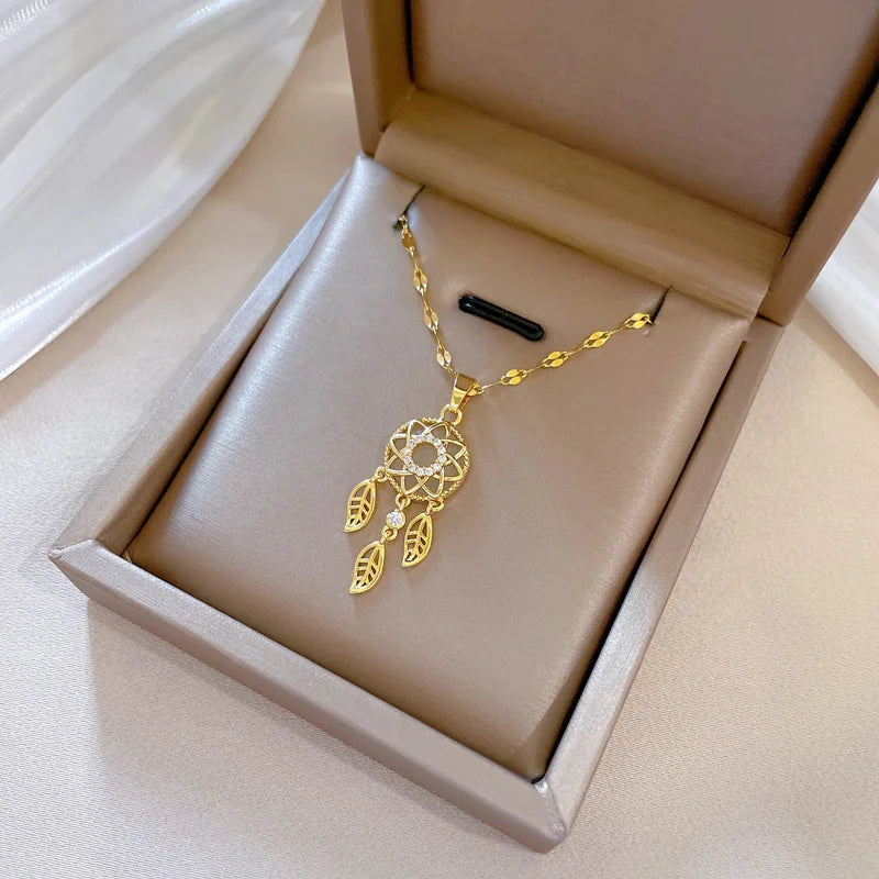 Gold necklace with a dreamcatcher design in an open jewelry box.