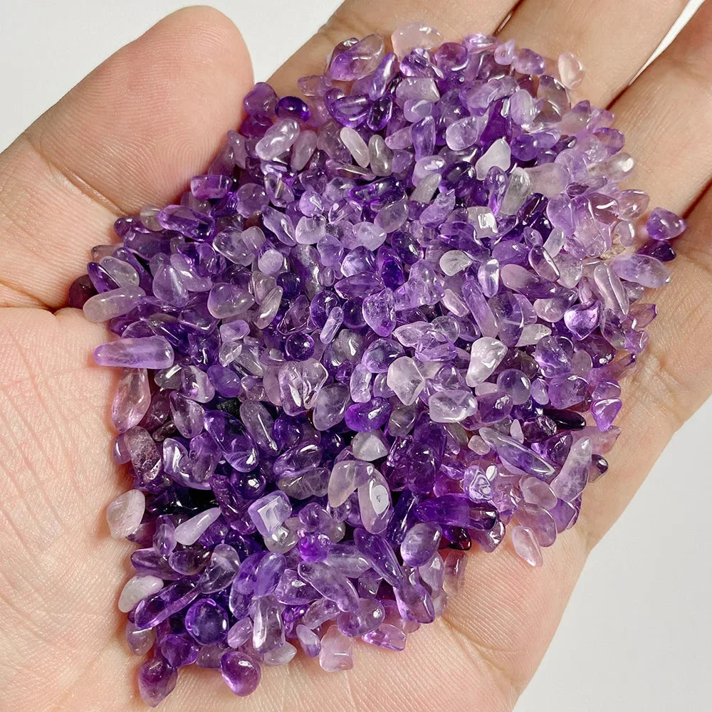 Hand holding a pile of purple crystals against a neutral background