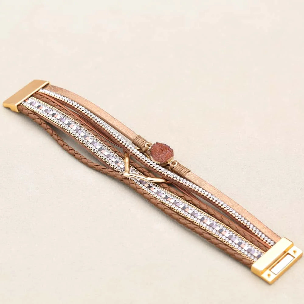 Bracelet with brown leather strap and gold accents on a beige background