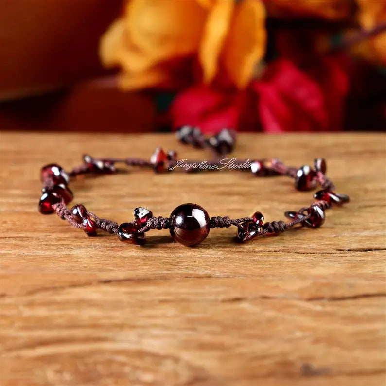 Garnet bracelet on a wooden surface with a blurred floral background