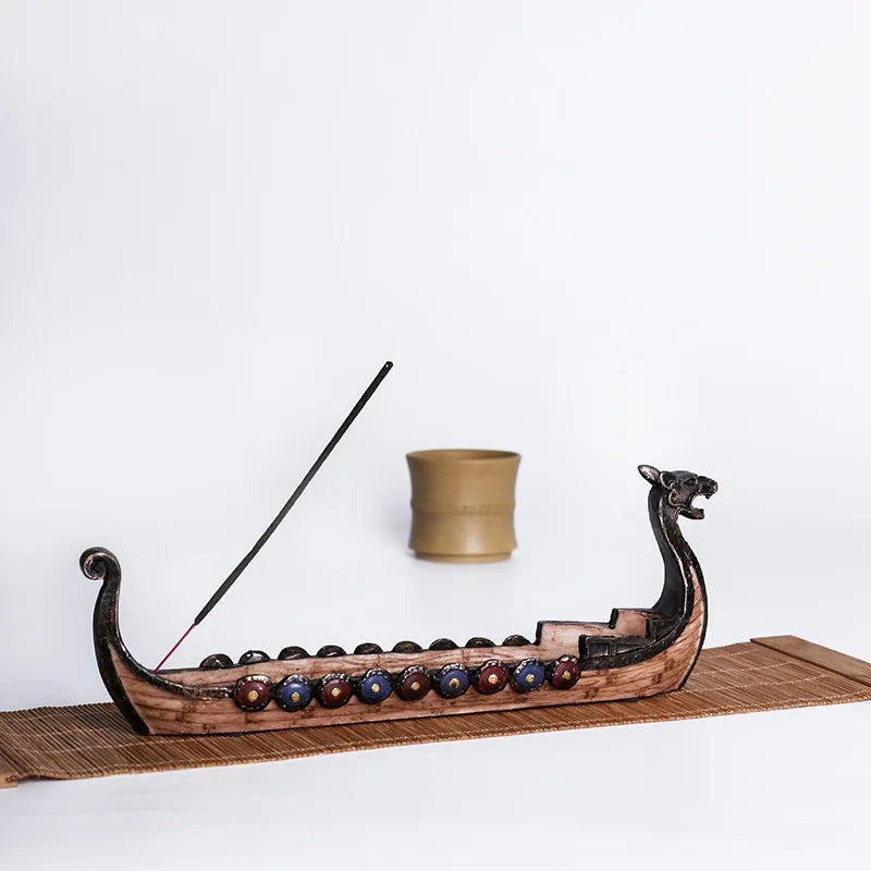 Wooden boat incense burner with a lit incense stick on a white background