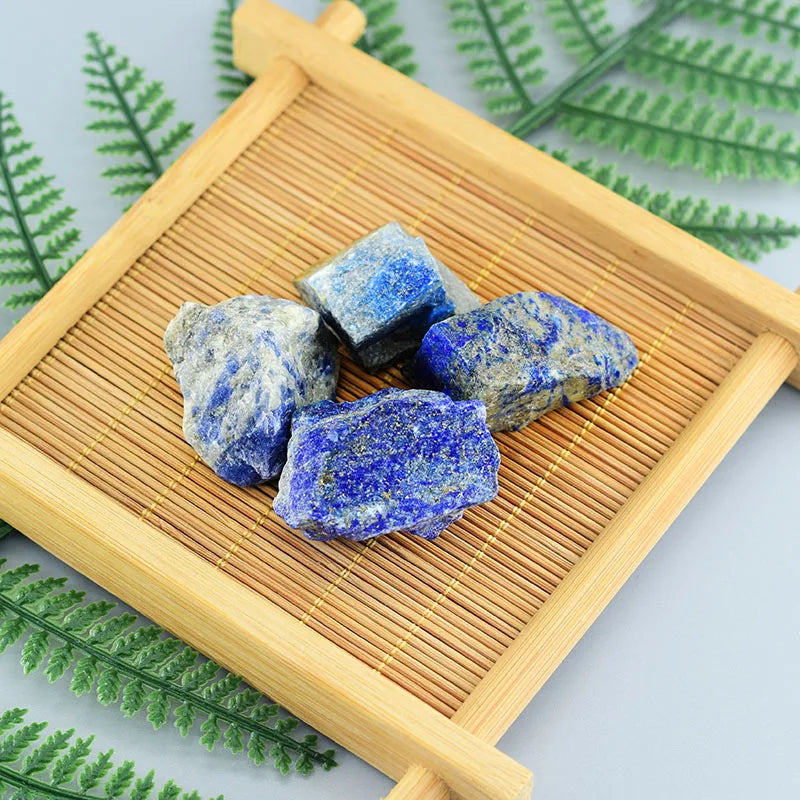 Blue stones on a wooden tray with green leaves in the background