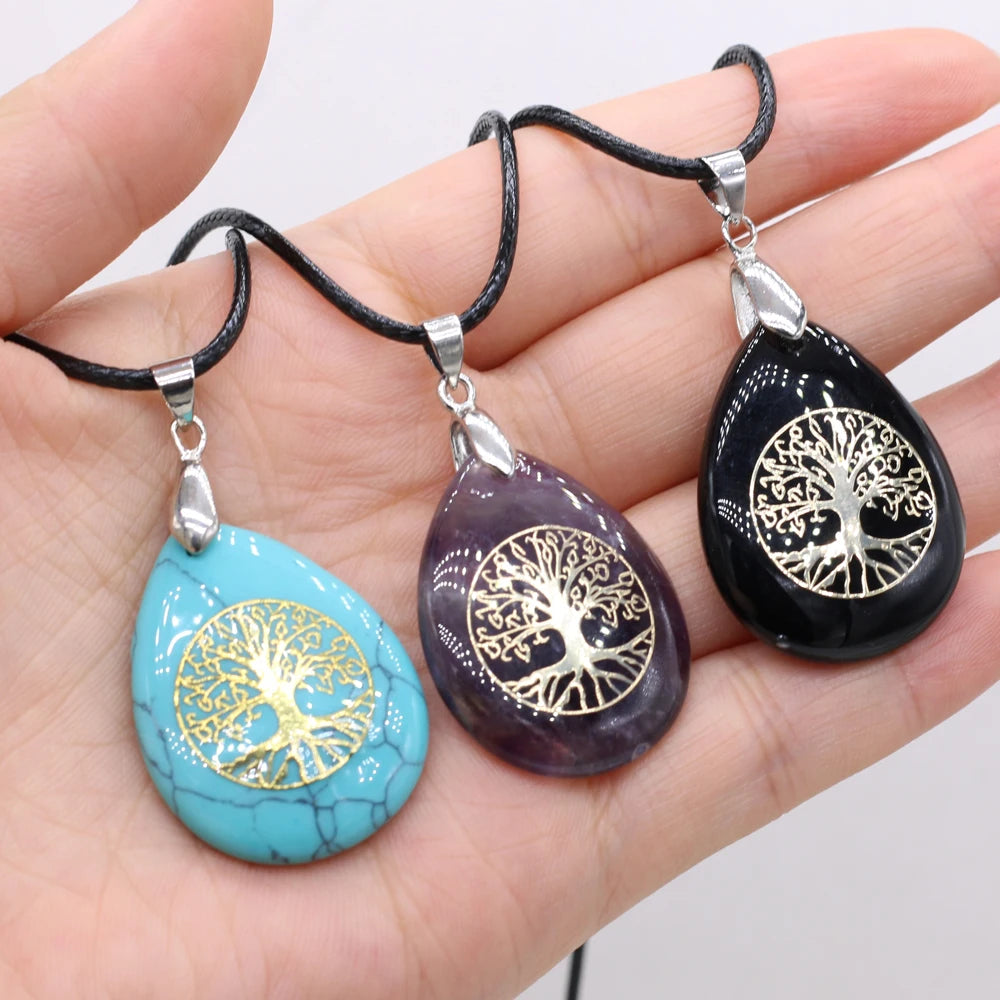 Three tree-of-life pendants on black cords held in a hand against a white background
