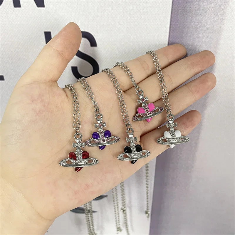 Hand holding multiple necklaces with various pendants against a blurred background
