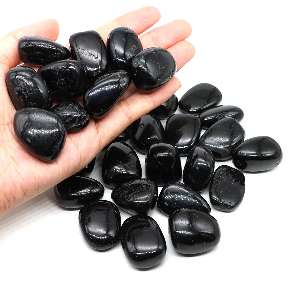 Hand holding a collection of black stones on a white background