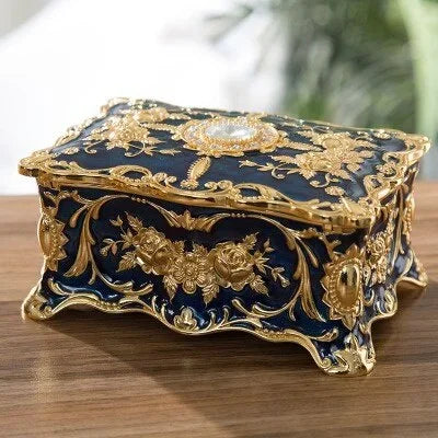 Decorative jewelry box with gold floral patterns on a wooden surface