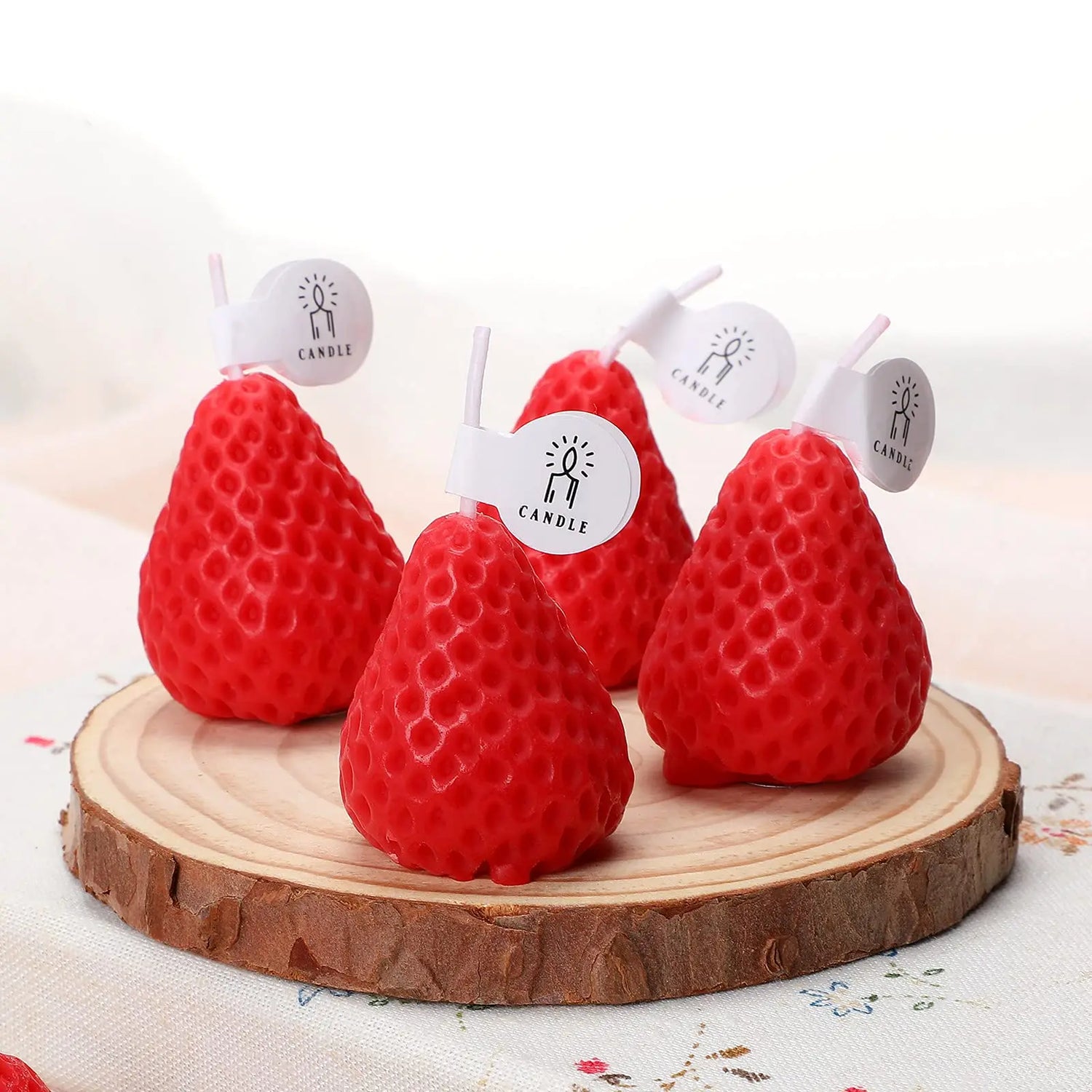 Red pear-shaped candles on a wooden base with a white background