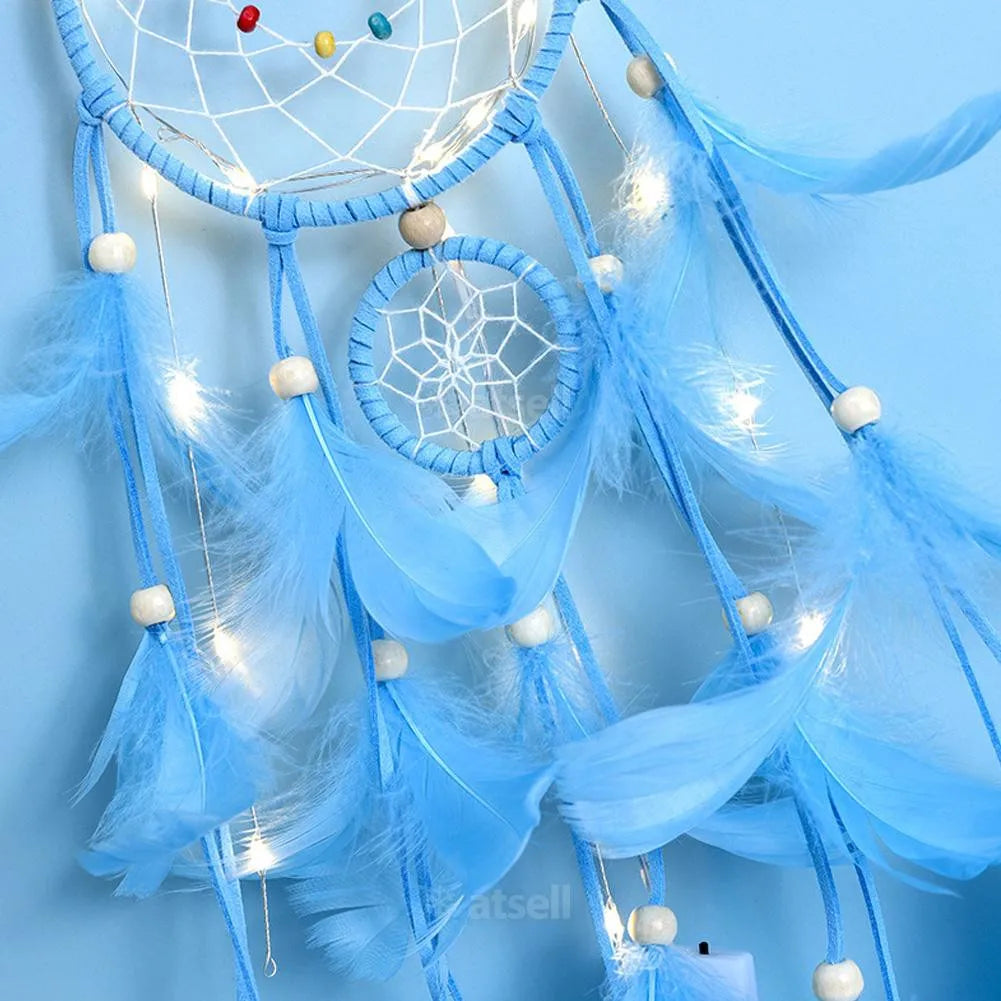 Blue dreamcatcher with feathers and lights against a light blue background